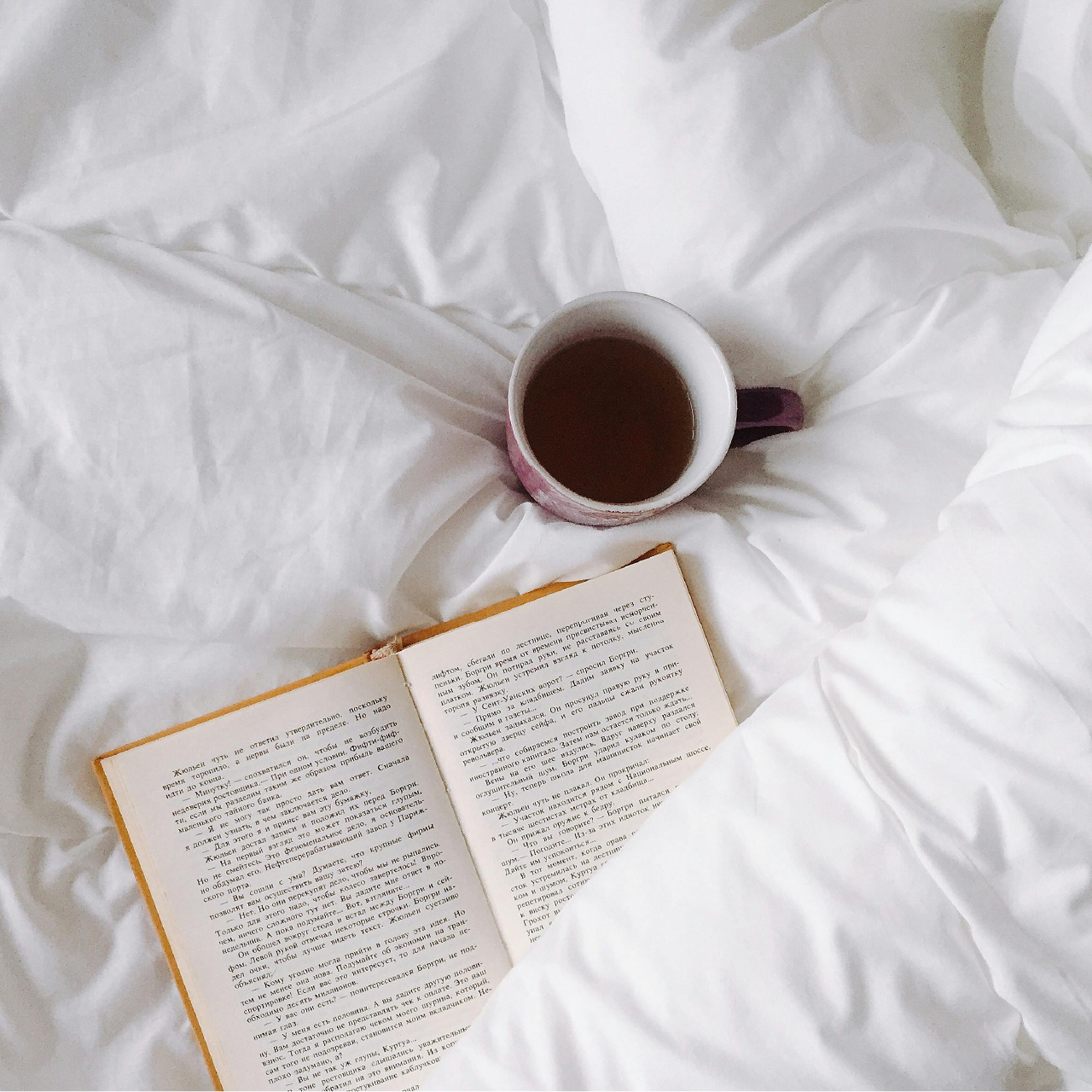 Cup of tea and book on a cozy bed, illustrating tea as part of a healthy, restorative routine.