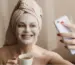 Smiling woman with a face mask and tea, showing how tea rituals aid skin care and relaxation.