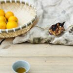 A ceramic teacup and fresh oranges arranged on a wooden table, evoking a warm seasonal tea moment