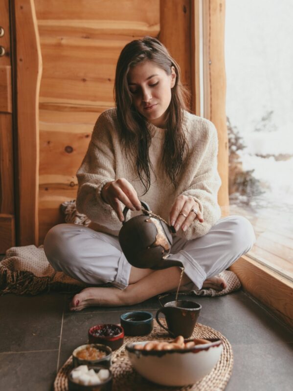Woman mindfully brewing tea in a cozy wooden cabin, embodying the harmony of nature and tea rituals