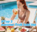 Woman sipping iced fruit tea by the pool, surrounded by fresh summer fruits