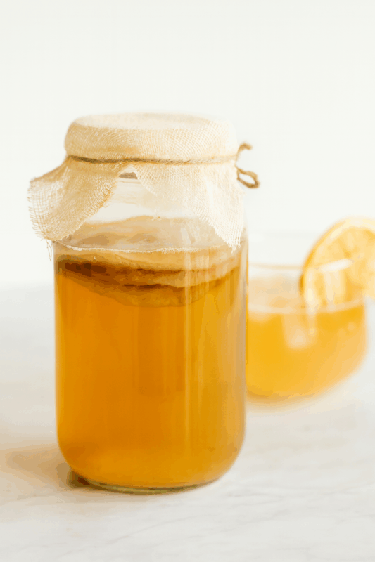 Glass jar of kombucha with SCOBY and natural bubbles