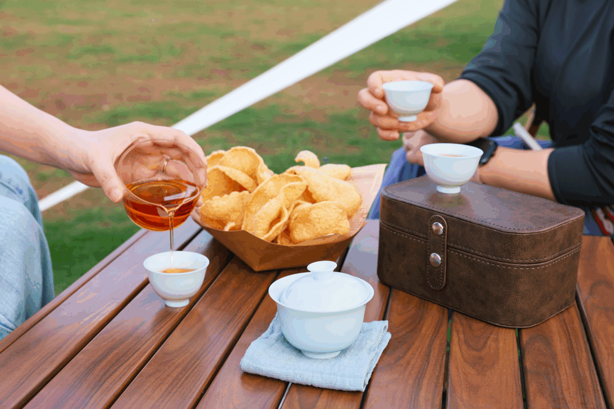 Portable porcelain gongfu tea set used outdoors by two people for a relaxed shared tea moment