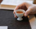 Person holding a small cup of warm Chinese tea during a quiet post-meal relaxation moment