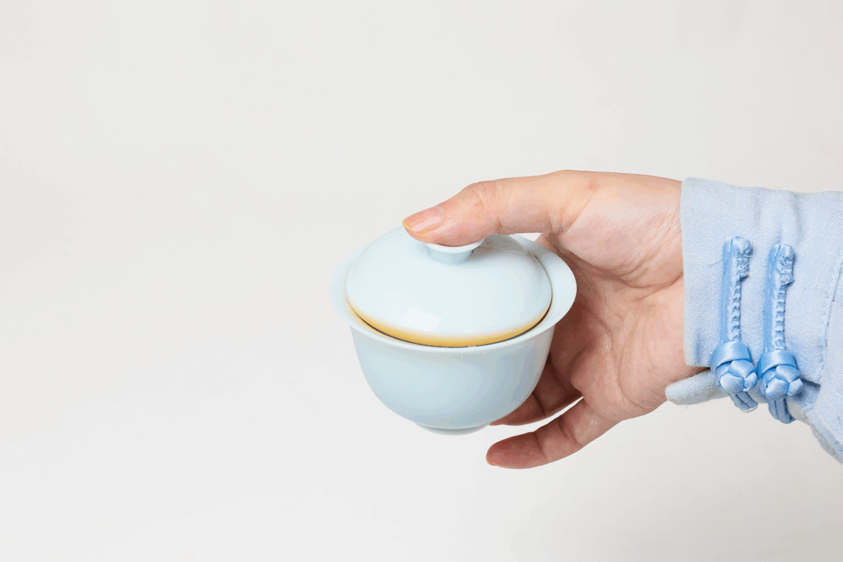 Instruction image showing correct gaiwan pouring in a portable porcelain gongfu tea set, including inner-wall pouring, comfortable grip, moderate opening, and natural tea flow