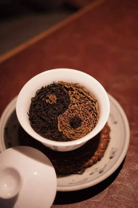 Tea leaves arranged in a yin-yang pattern in a gaiwan, illustrating balance and tea choice after meals