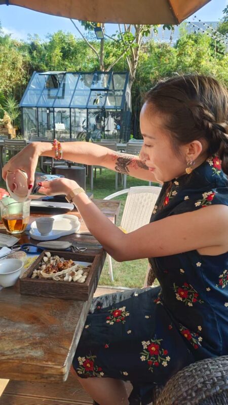 Brewing Chinese tea outdoors during a relaxed gongfu tea session with quiet attention and slow movement.