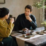 Two people drinking Chinese tea indoors after a meal, illustrating how black tea and rock tea fit different post-meal situations