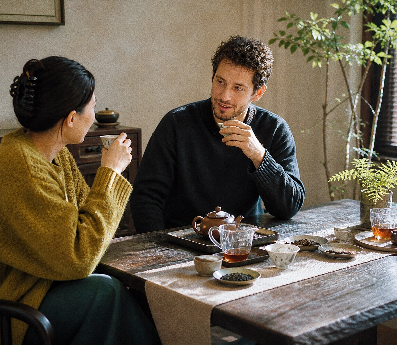 Two people drinking Chinese tea indoors after a meal, illustrating how black tea and rock tea fit different post-meal situations