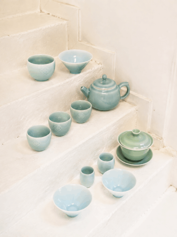A Longquan celadon tea set arranged in a minimalist space, showing how the jade-like glaze interacts with light, table setting, and tea rituals.