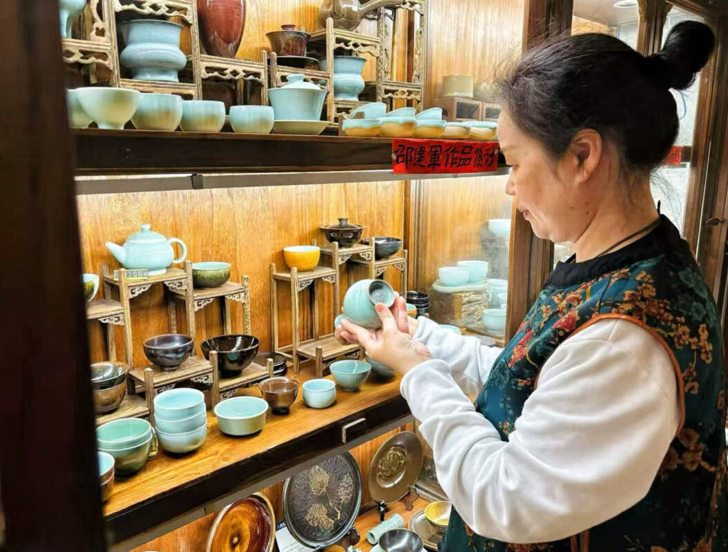 Pan Junli examining celadon teaware in Longquan, connecting Chinese tea culture with vessel, temperature, and mood.