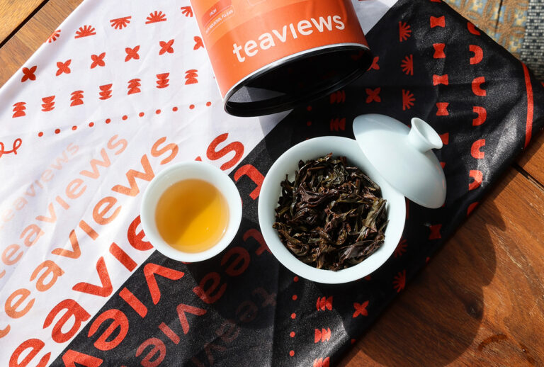 Teaviews Chinese tea set with gaiwan, tea leaves, and branded packaging on an outdoor table, showing tea adapted for modern everyday life.