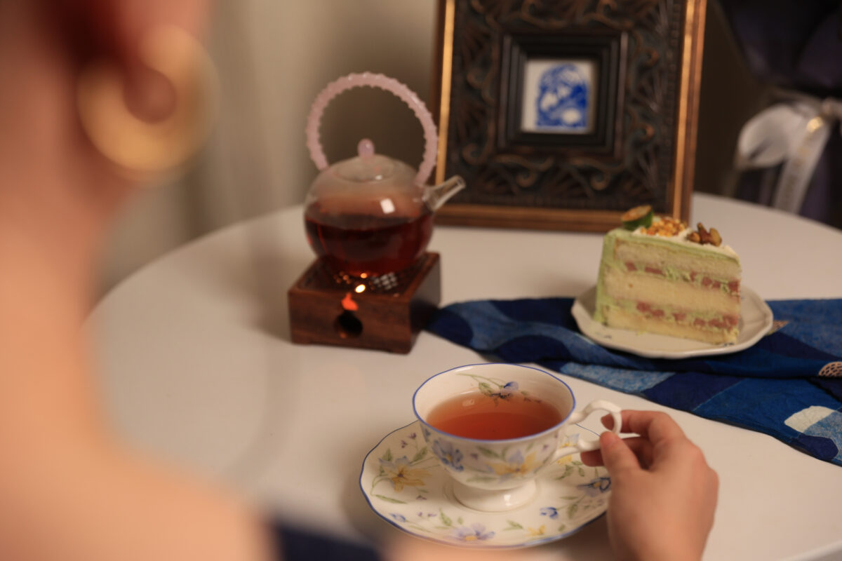 A cup of Gong Mei white tea served with cake during a relaxing afternoon tea, showing its amber liquor and soft, naturally sweet character.