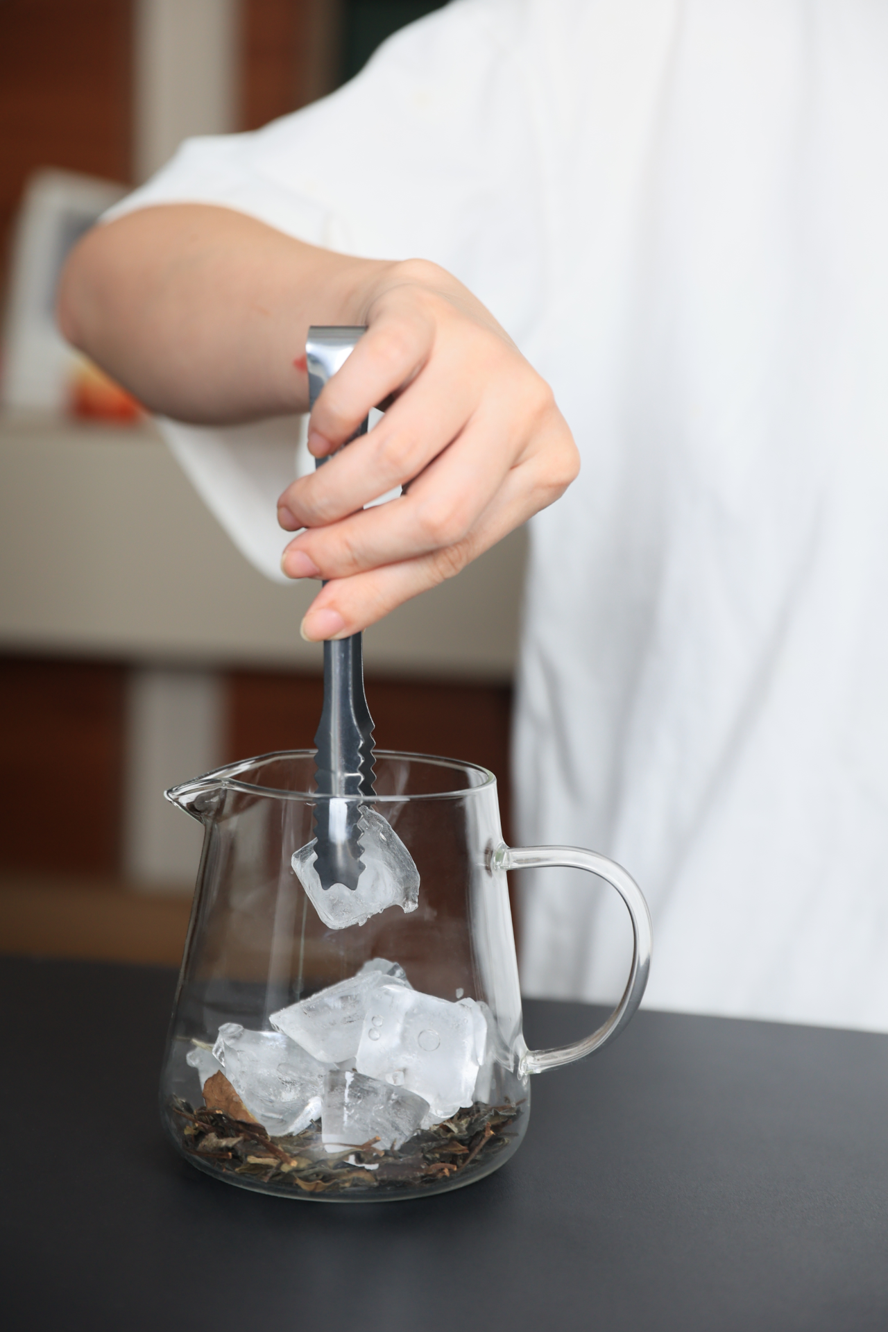 Preparing cold brew Gong Mei white tea with ice in a glass pitcher for a clean, refreshing, naturally sweet summer drink.