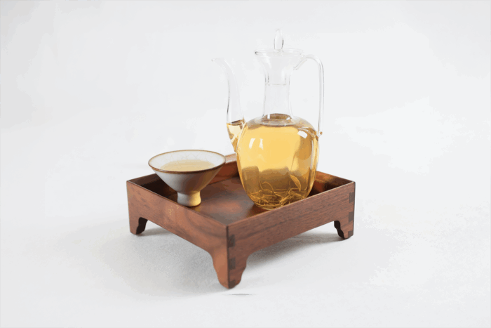 Hengxian Jasmine Tea brewed in a glass cup on a wooden tea tray.