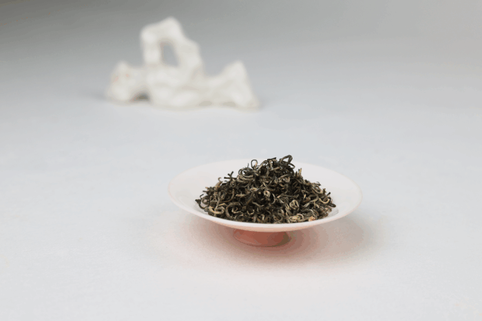 Dry Hengxian Jasmine Tea leaves displayed on a small dish.