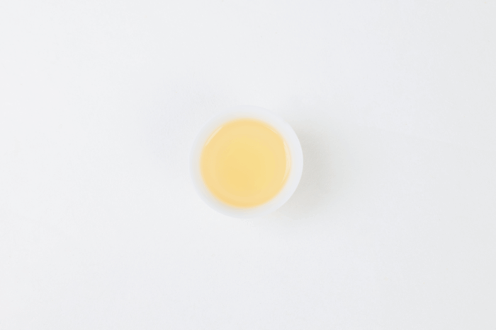 Clear pale yellow-green liquor of Hengxian Jasmine Tea viewed from above.