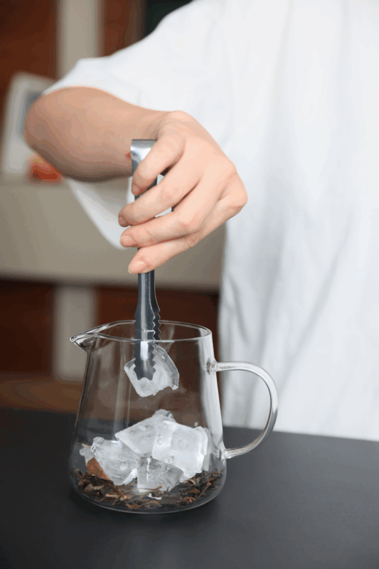 Adding ice cubes to brewed Chinese tea for hot brew flash-chill iced tea