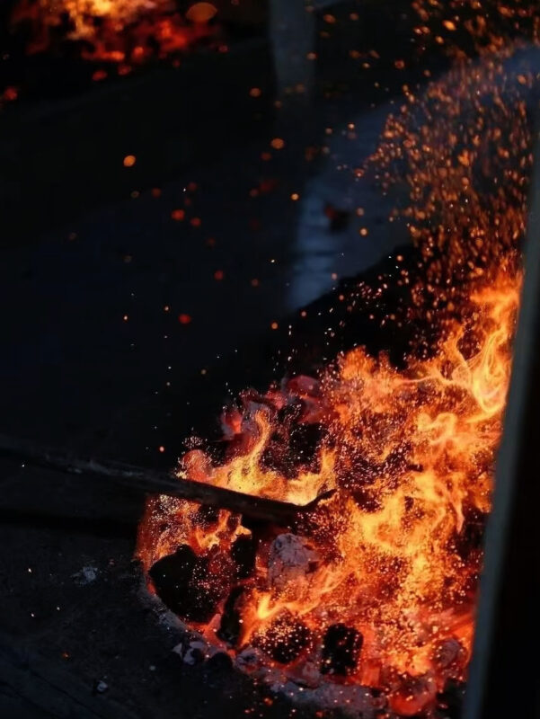 Traditional charcoal roasting process of Wuyi rock tea showing intense heat and fire during the Yancha roasting stage.