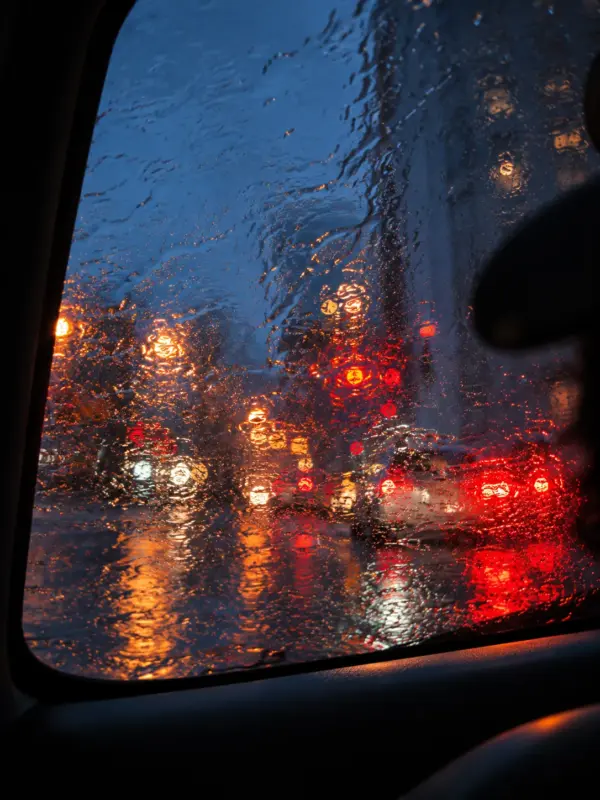 Rain running down a car window at dusk, blurring city lights during a personal experience of depression, anxiety and feeling disconnected from the world.