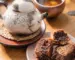 A ceramic teapot, cup of tea and pastries in warm light, representing tea, body awareness and sensory grounding during depression.