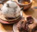 A ceramic teapot, cup of tea and pastries in warm light, representing tea, body awareness and sensory grounding during depression.